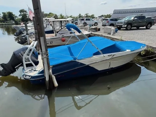 Slide: The Image of 2021 Glastron GX 210 Sport boat docked with blue cover in a marina. - 2