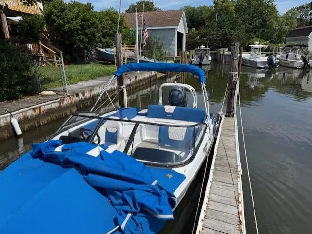 Slide: The Image of 2021 Glastron GX 210 Sport boat docked in a serene marina setting. - 5