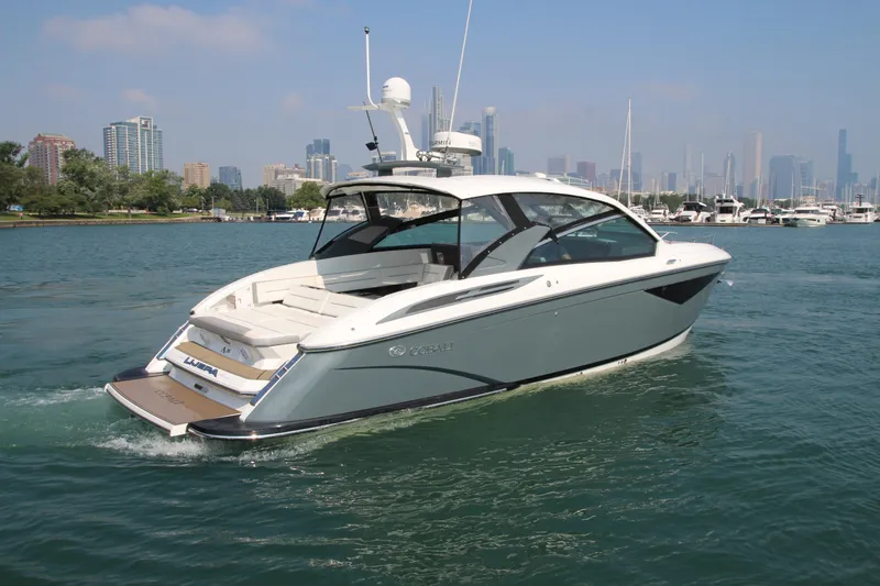 Slide: The Image of 2018 Cobalt A36 boat cruising near city skyline on a sunny day. - 2