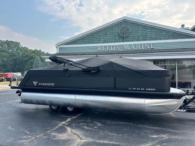 Slide: The Image of 2025 Viaggio Lago X-F pontoon boat covered, parked at Reed's Marine dealership. - 26