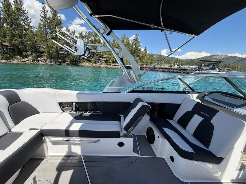 Slide: The Image of 2021 MasterCraft X24 boat interior with sleek seating, dockside view, and clear blue water. - 10