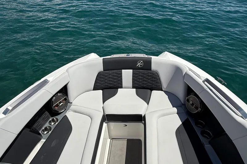 Slide: The Image of 2021 MasterCraft X24 boat interior with luxurious seating and cup holders on a calm lake. - 11