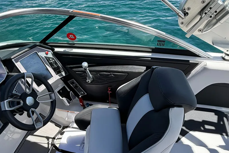 Slide: The Image of 2021 MasterCraft X24 boat interior with steering wheel and control panel, overlooking water. - 8