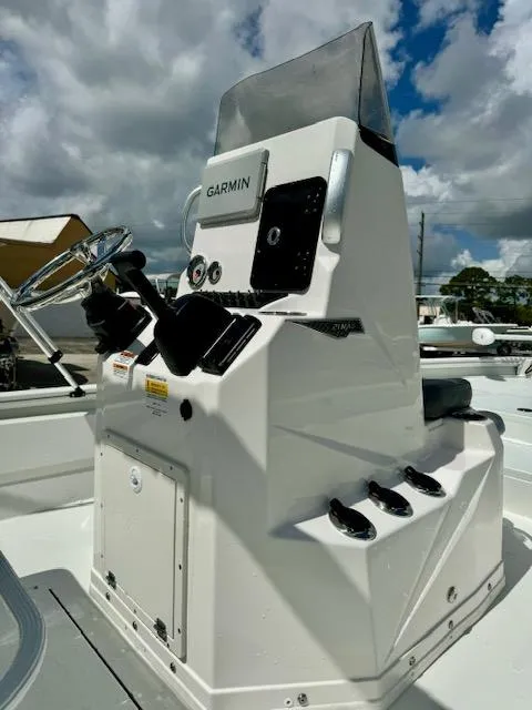 Slide: The Image of Avid 21 Mag 2025 boat console with Garmin navigation, steering wheel, and controls under cloudy sky. - 11