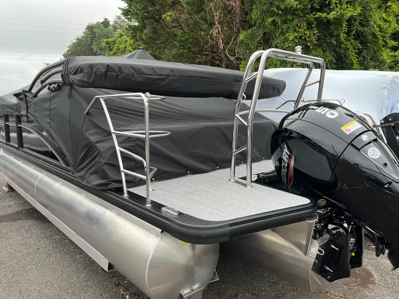 Slide: The Image of 2026 Harris Cruiser 230 pontoon boat with covered seating and outboard motor, parked outdoors. - 3