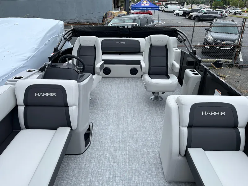 Slide: The Image of 2026 Harris Cruiser 230 boat interior with gray and white seating, parked outdoors. - 6