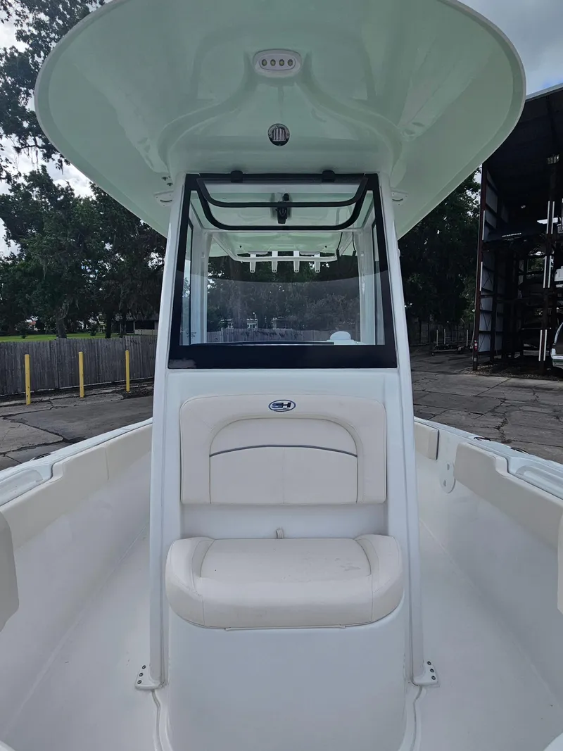 Slide: The Image of 2025 Sea Hunt Ultra 235 SE boat interior with seating and console, docked outdoors. - 20