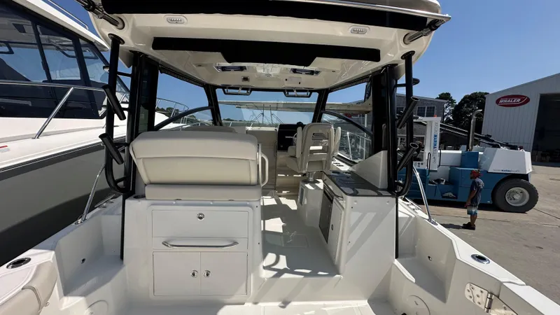 Slide: The Image of 2026 Boston Whaler 325 Conquest boat interior, featuring seating and storage, docked outdoors. - 17