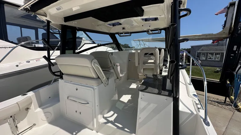 Slide: The Image of 2026 Boston Whaler 325 Conquest interior with seating and helm, docked under clear skies. - 18