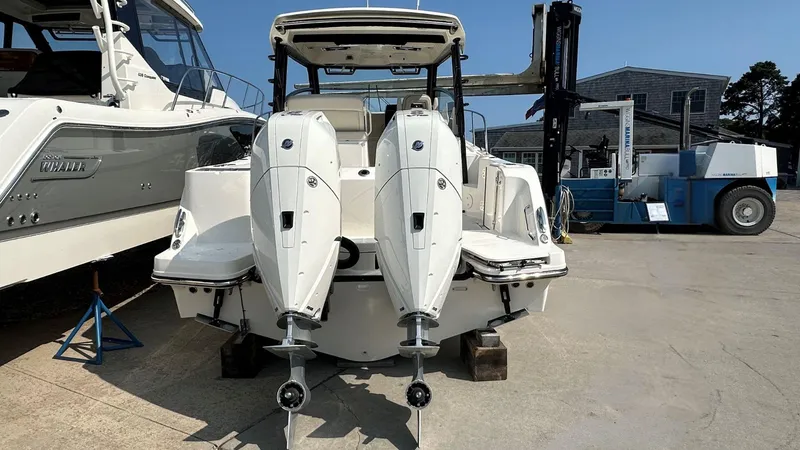 Slide: The Image of 2026 Boston Whaler 325 Conquest boat with dual outboard engines in a marina setting. - 2