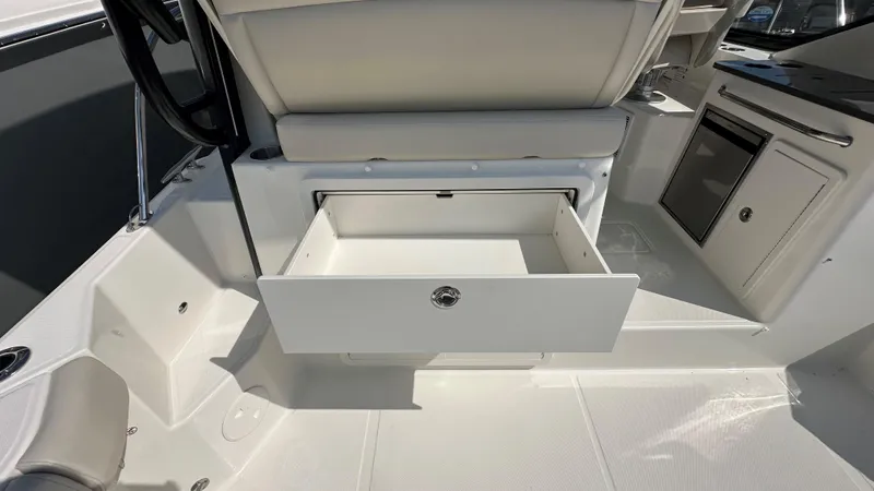 Slide: The Image of 2026 Boston Whaler 325 Conquest interior with open storage drawer and seating. - 22
