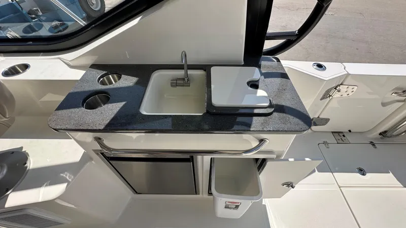 Slide: The Image of 2026 Boston Whaler 325 Conquest boat kitchenette with sink, countertop, and storage compartments. - 26