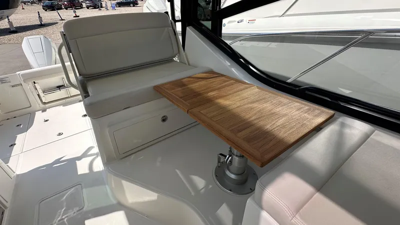 Slide: The Image of 2026 Boston Whaler 325 Conquest interior with wooden table and cushioned seating. - 31