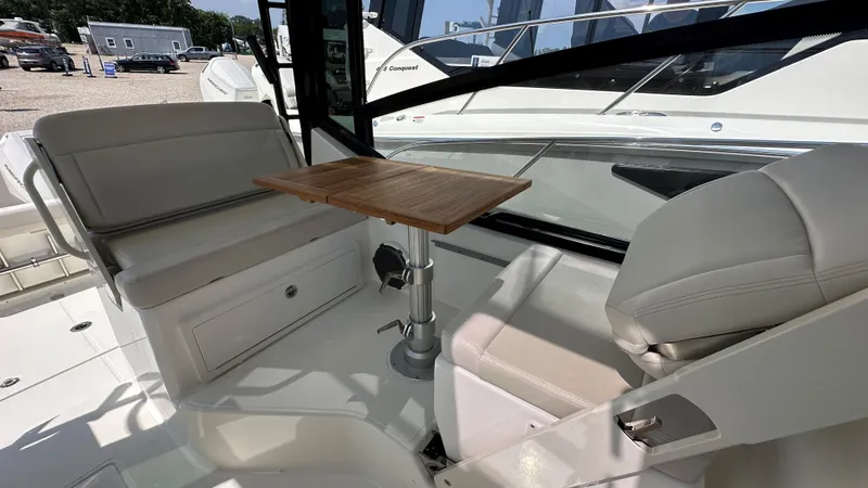 Slide: The Image of 2026 Boston Whaler 325 Conquest interior with seating and wooden table. - 32