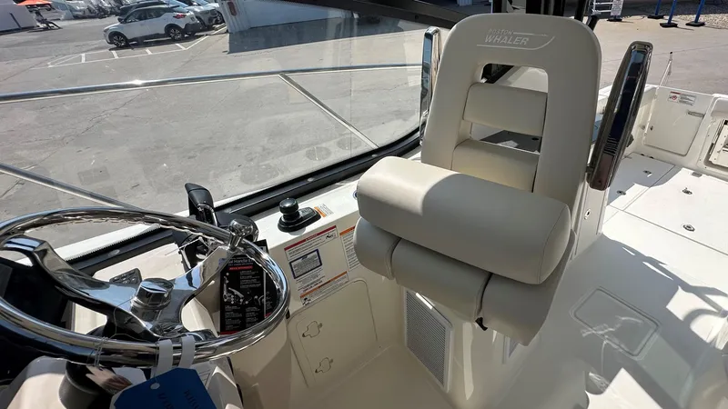 Slide: The Image of 2026 Boston Whaler 325 Conquest helm with steering wheel and cushioned captain's chair. - 34