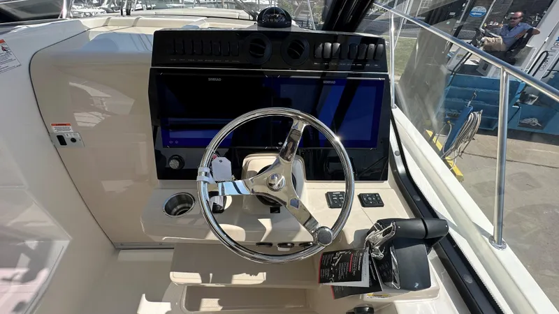 Slide: The Image of 2026 Boston Whaler 325 Conquest helm with steering wheel and navigation display. - 37