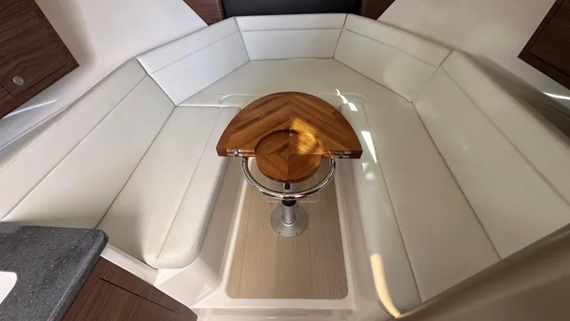Slide: The Image of 2026 Boston Whaler 325 Conquest interior with white seating and wooden table. - 39