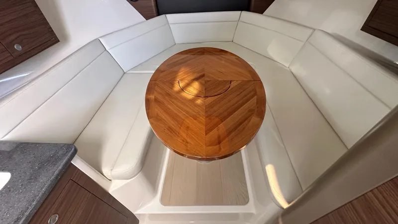 Slide: The Image of 2026 Boston Whaler 325 Conquest interior with white seating and wooden table. - 40