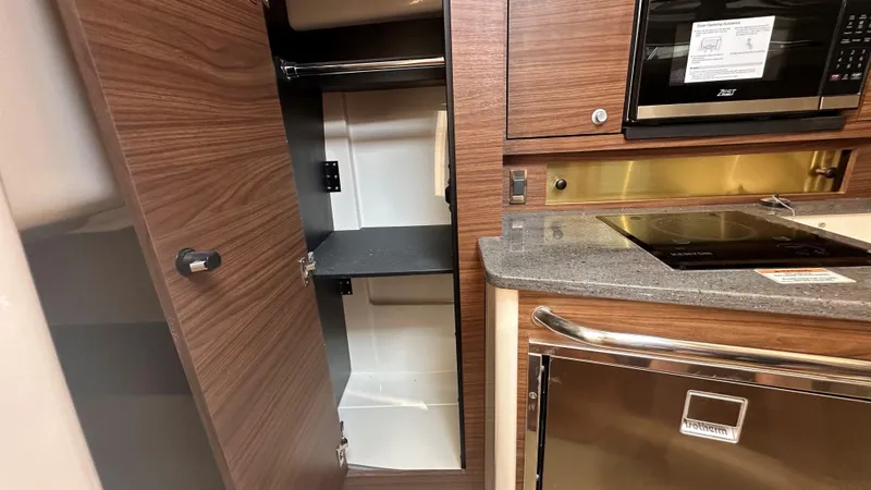 Slide: The Image of Interior of 2026 Boston Whaler 325 Conquest, featuring modern kitchen cabinetry and appliances. - 49
