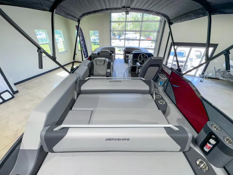 Slide: The Image of 2025 Berkshire 23SBE STS pontoon boat interior with seating and helm, in showroom. - 17