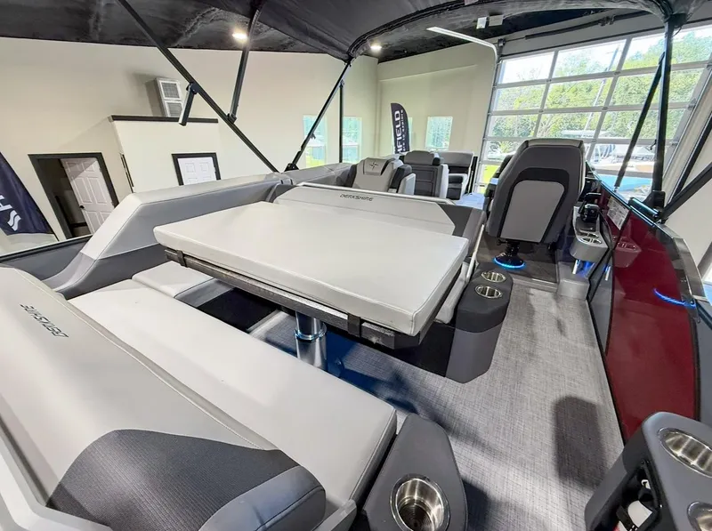 Slide: The Image of 2025 Berkshire 23SBE STS boat interior with seating and table in showroom. - 26