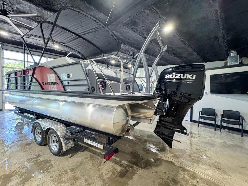 Slide: The Image of 2025 Berkshire 23SBE STS pontoon boat with Suzuki outboard motor on trailer in showroom. - 4