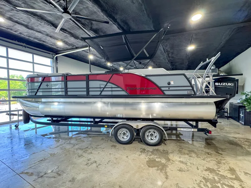 Slide: The Image of 2025 Berkshire 23SBE STS pontoon boat in showroom, featuring sleek design and Suzuki engine. - 5