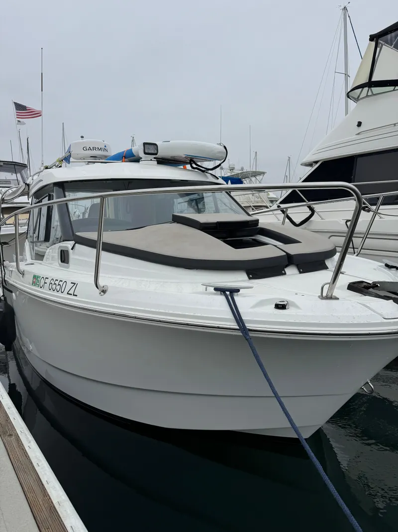 Slide: The Image of 2020 Jeanneau NC 795 boat docked at marina with American flag in background. - 1