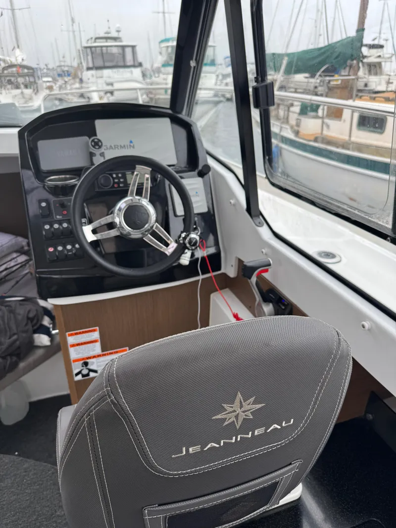Slide: The Image of 2020 Jeanneau NC 795 boat interior with steering wheel and dashboard in marina setting. - 39