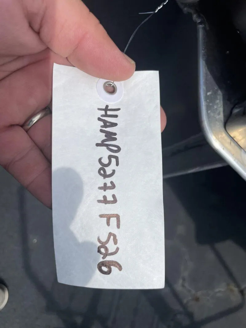 Slide: The Image of Hand holding a tag with handwritten code, near a Harris Cruiser 230, 2026 model. - 19