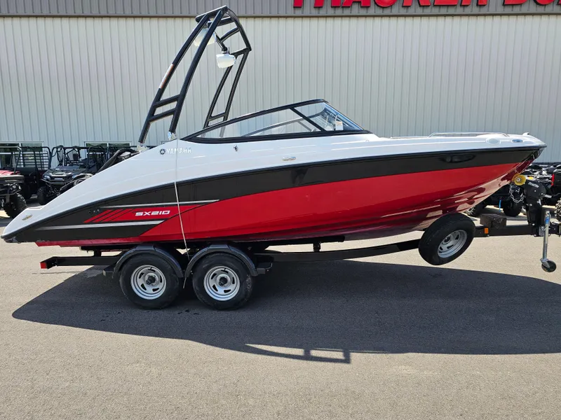 The Image of 2017 Yamaha Boats SX210 on trailer, red and white design, parked outdoors. - 0