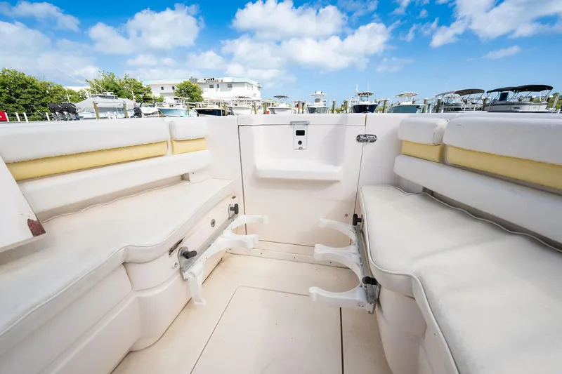 Slide: The Image of 2009 Intrepid 323 CC boat interior with white seating and rod holders, docked under blue skies. - 13