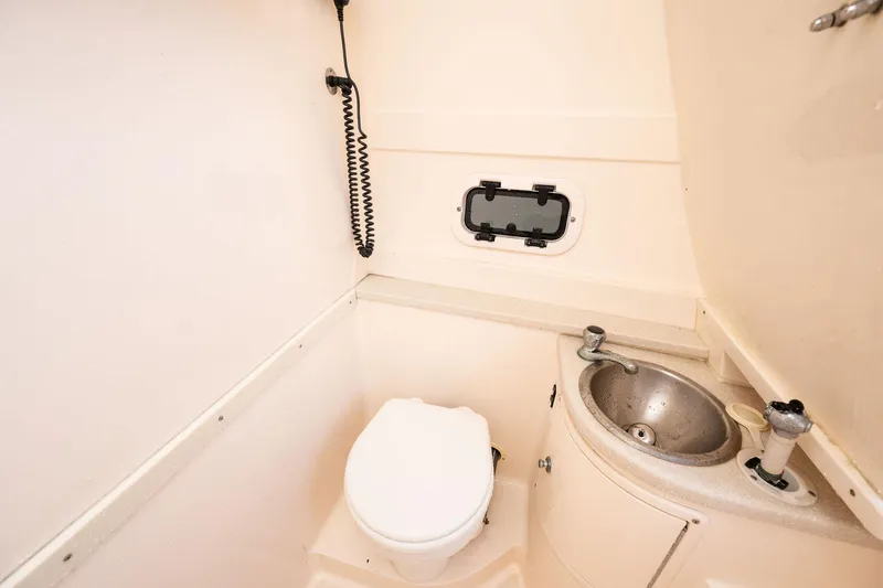Slide: The Image of 2009 Intrepid 323 CC boat bathroom with toilet, sink, and porthole window. - 17