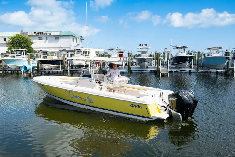 Slide: The Image of 2009 Intrepid 323 CC boat docked in marina, featuring dual Mercury engines. - 19