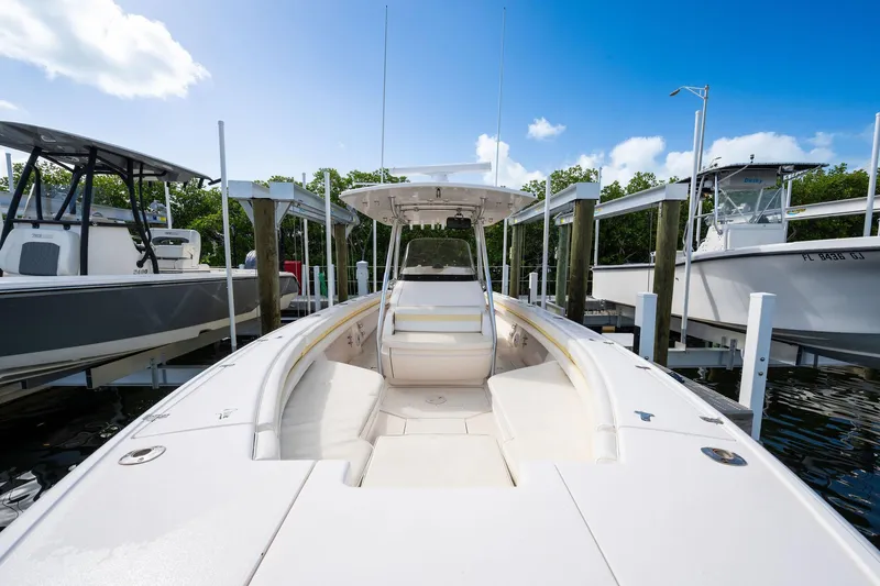 Slide: The Image of 2009 Intrepid 323 CC boat docked, featuring spacious deck and sleek design under clear blue sky. - 2