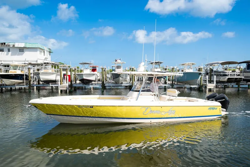 Slide: The Image of 2009 Intrepid 323 CC boat in marina, yellow hull, clear sky background. - 21