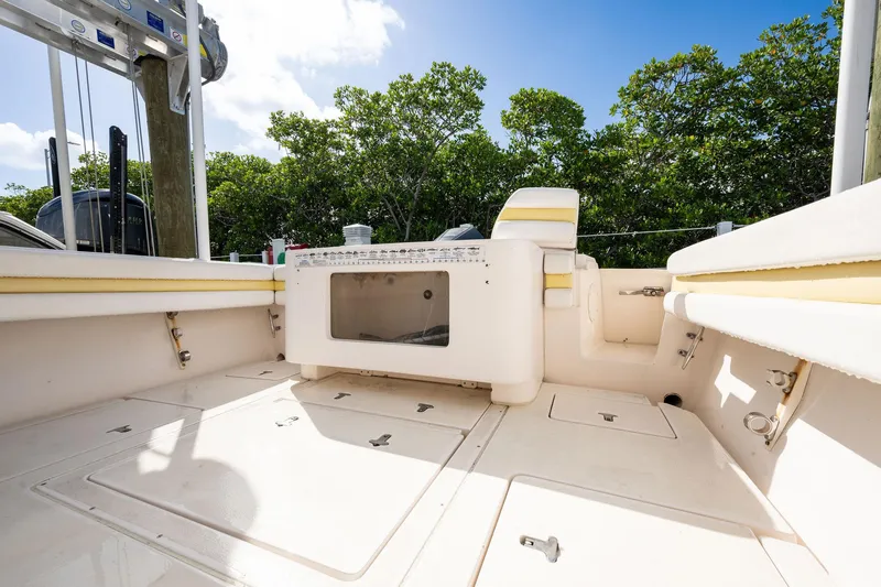 Slide: The Image of 2009 Intrepid 323 CC boat deck with storage compartments and seating, surrounded by greenery. - 23