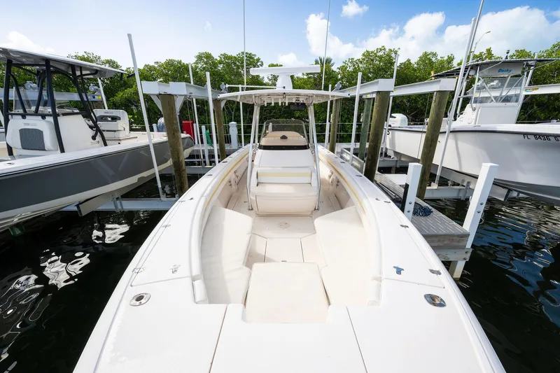 Slide: The Image of 2009 Intrepid 323 CC boat docked, showcasing spacious deck and seating under clear skies. - 24