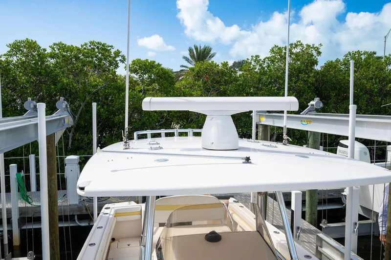 Slide: The Image of 2009 Intrepid 323 CC boat docked, featuring radar equipment and lush greenery in the background. - 25