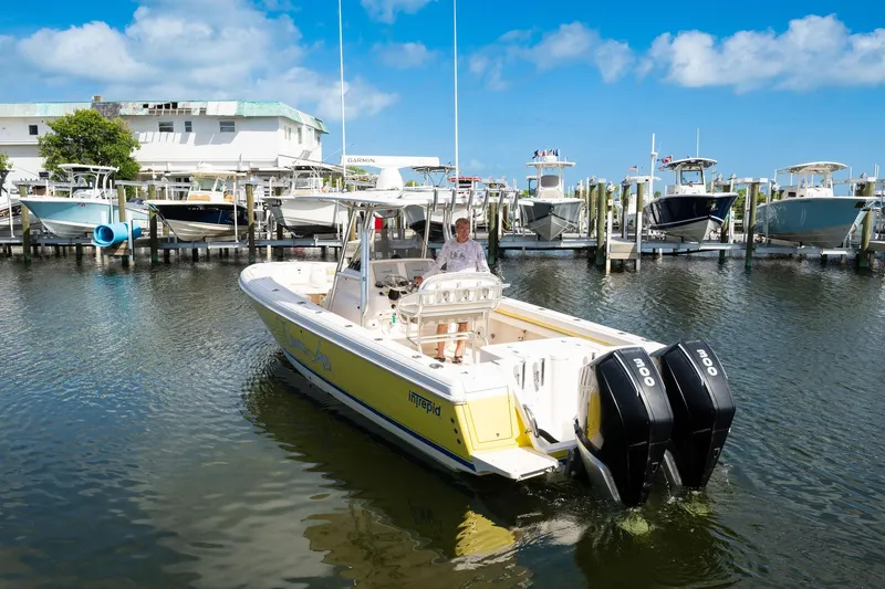 Slide: The Image of 2009 Intrepid 323 CC boat docked in marina, clear sky, multiple boats in background. - 26