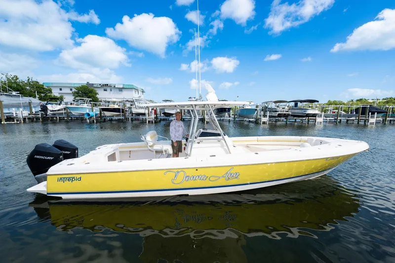 Slide: The Image of 2009 Intrepid 323 CC boat docked, yellow hull, clear sky, calm water, marina background. - 31