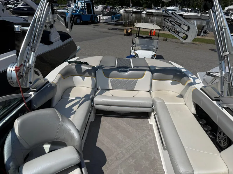 Slide: The Image of 2015 MasterCraft X10 boat interior with plush seating and sleek design at a marina. - 4