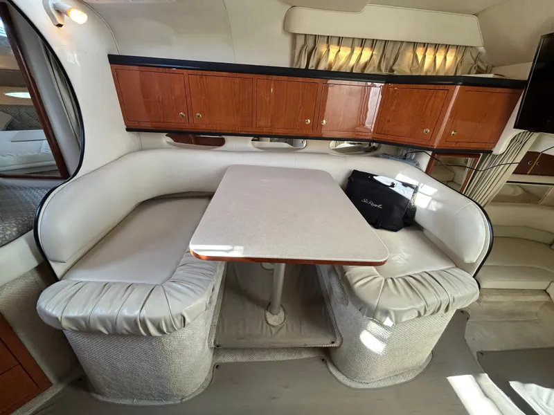 Slide: The Image of Interior of 2001 Sea Ray 310 Sundancer with dining area and wooden cabinets. - 11