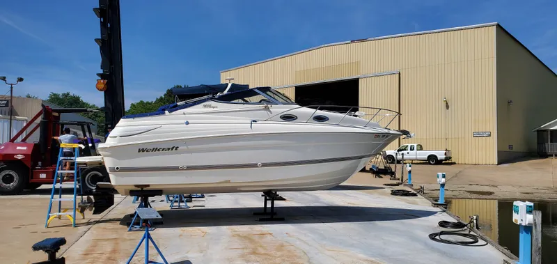 Slide: The Image of 2003 Wellcraft 2400 Martinique boat on dry dock near a warehouse. - 1