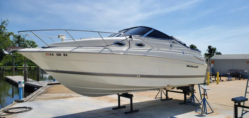 Slide: The Image of 2003 Wellcraft 2400 Martinique boat on stands at a marina, clear sky background. - 3
