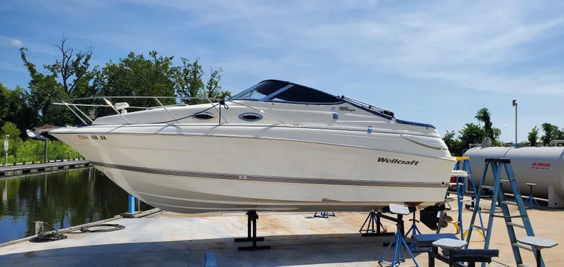 Slide: The Image of 2003 Wellcraft 2400 Martinique boat on dry dock, sunny day, marina background. - 4