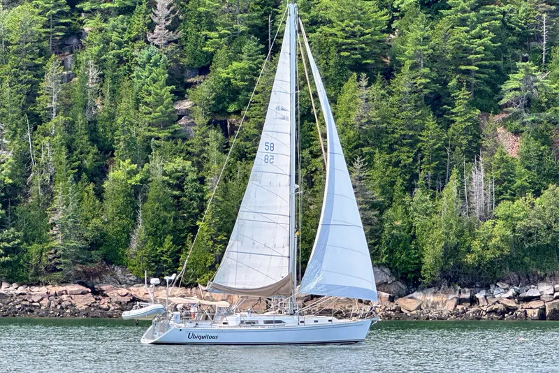 The Image of Sailboat "Ubiquitous" docked, Outbound 46 model, 2015, with tan sails and calm waters. - 0