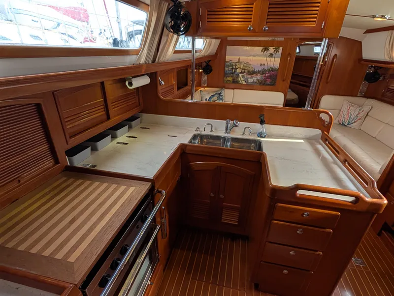 Slide: The Image of Galley of 2015 Outbound 46 yacht with open fridge, sink, and wooden cabinetry. - 6