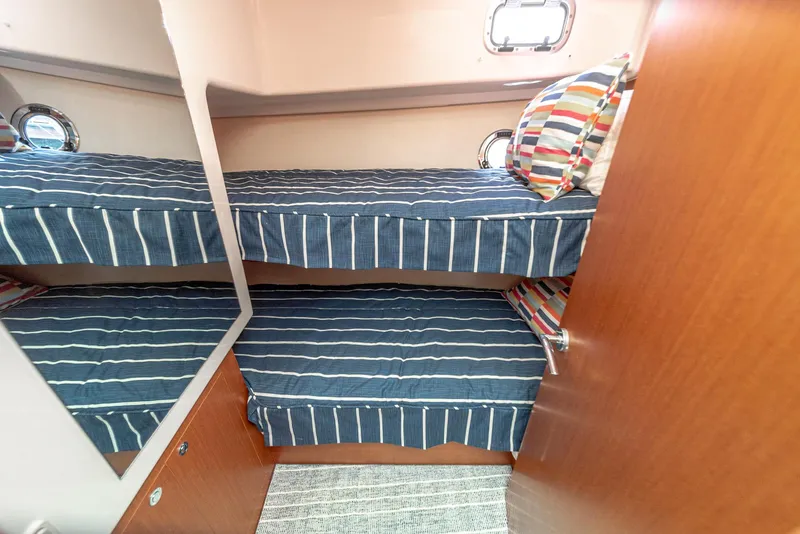 Slide: The Image of 2014 Beneteau Swift Trawler 34 cabin with bunk beds and striped bedding. - 18