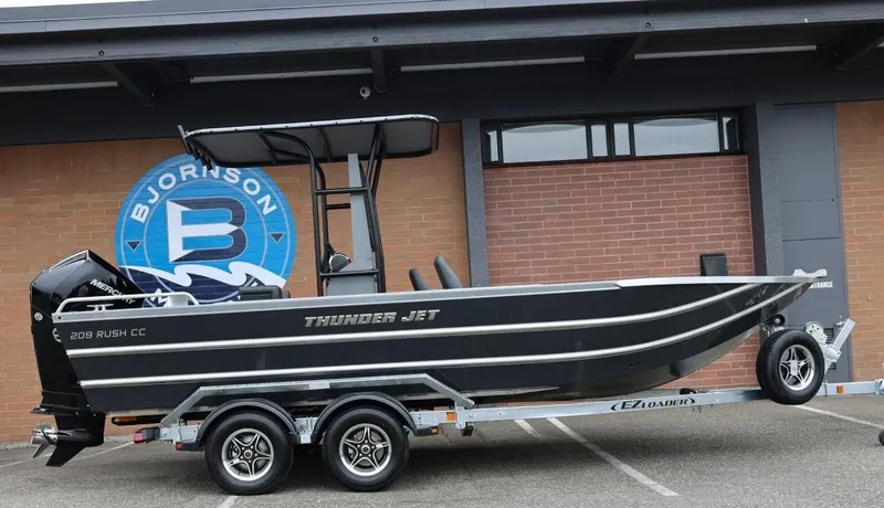 The Image of 2026 Thunder Jet 209 Rush Center Console boat on trailer, parked outside a building. - 1